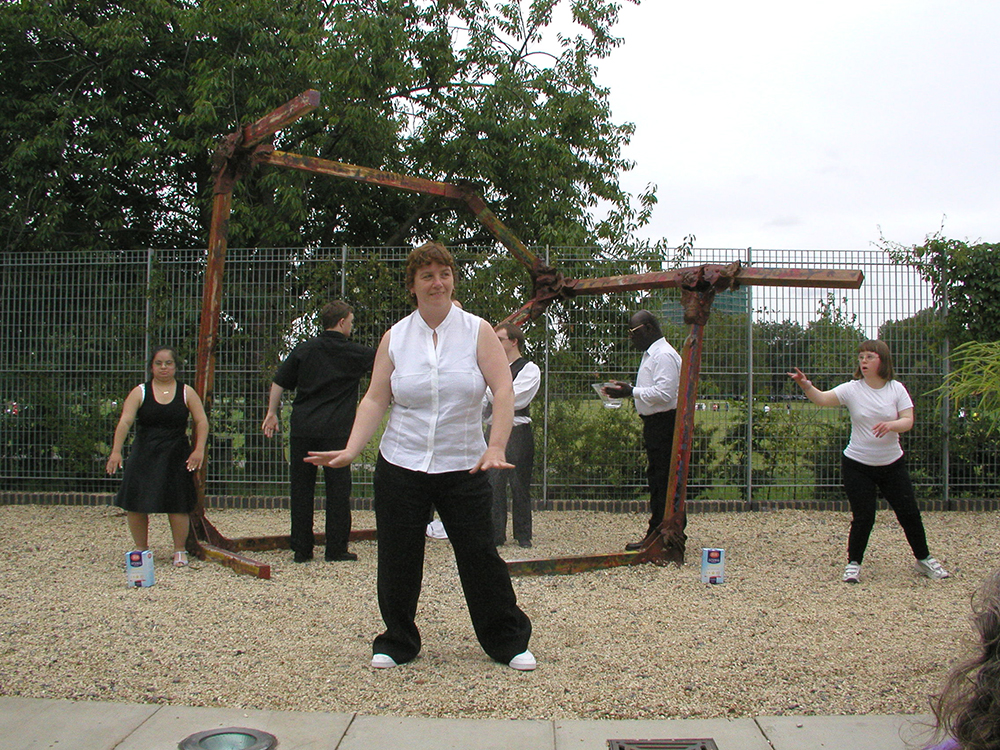 Aisha Booth, John Long, Jackie Ryan, Nick McKerrow, Dennis Plummer, Bethan Kendrick performing around a metal sculpture in the garden of Café Gallery Projects as part of the performance by Corali Dance Company called Slither & Slice 2004